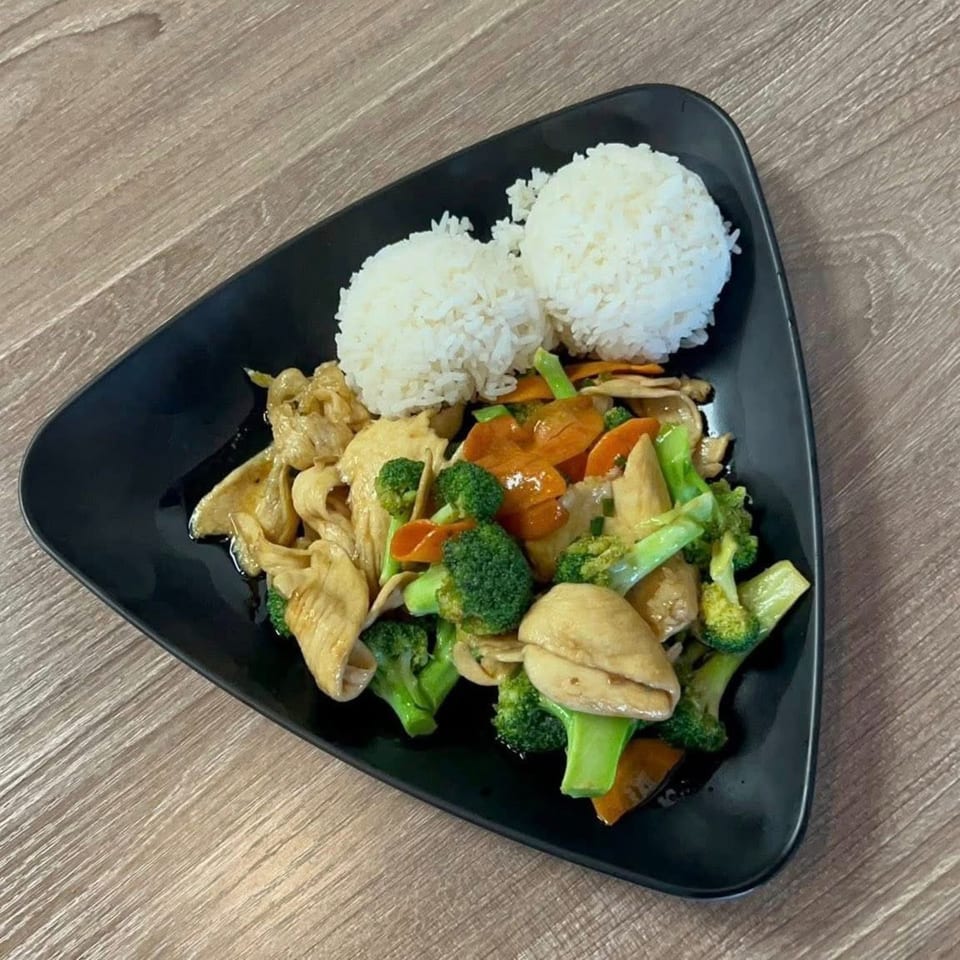 Chicken and broccoli stir-fry with carrots and mushrooms, served with two scoops of white rice.