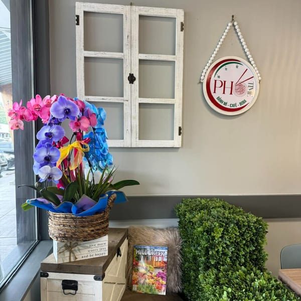 Colorful orchids, a decorative window, and a "Pho Time" clock adorn the restaurant interior.