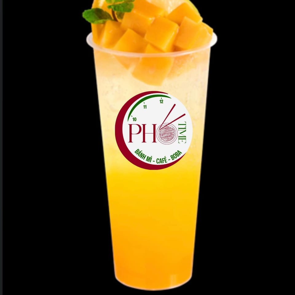 A Pho Time mango drink with diced mango and mint leaves, against a black background.