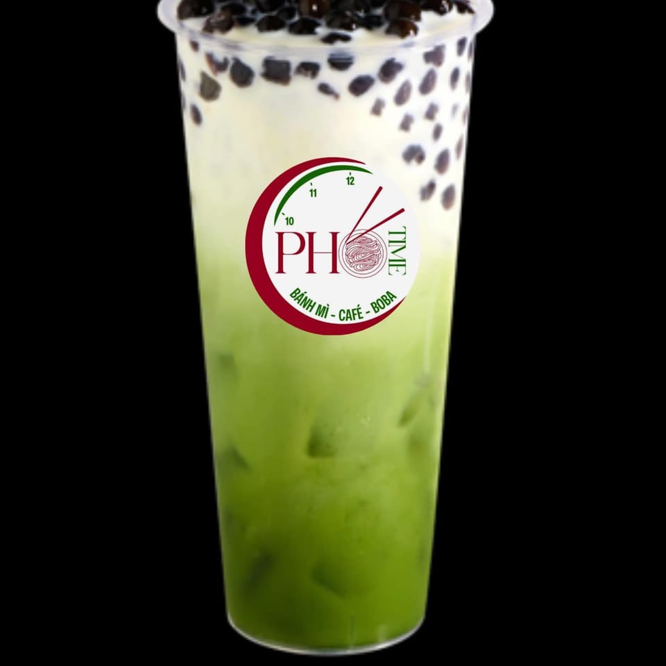 A Pho Time matcha boba drink with a green bottom layer, white top layer, and black boba pearls.