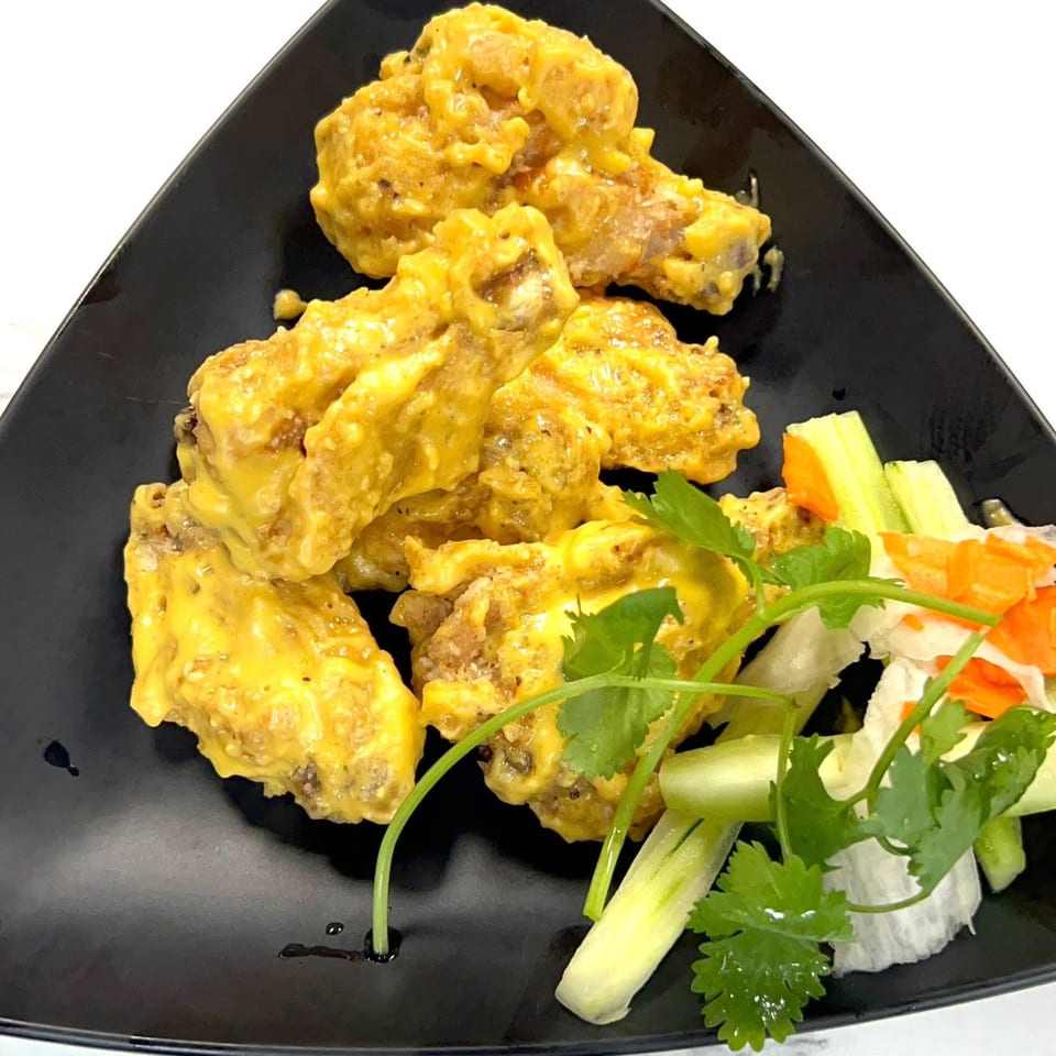 Golden chicken wings coated in a rich sauce, served with fresh cilantro and pickled vegetables.